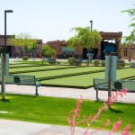 Well-maintained outdoor bocce ball courts lined next to one another. Clean cut, green grass and paved walkways.
