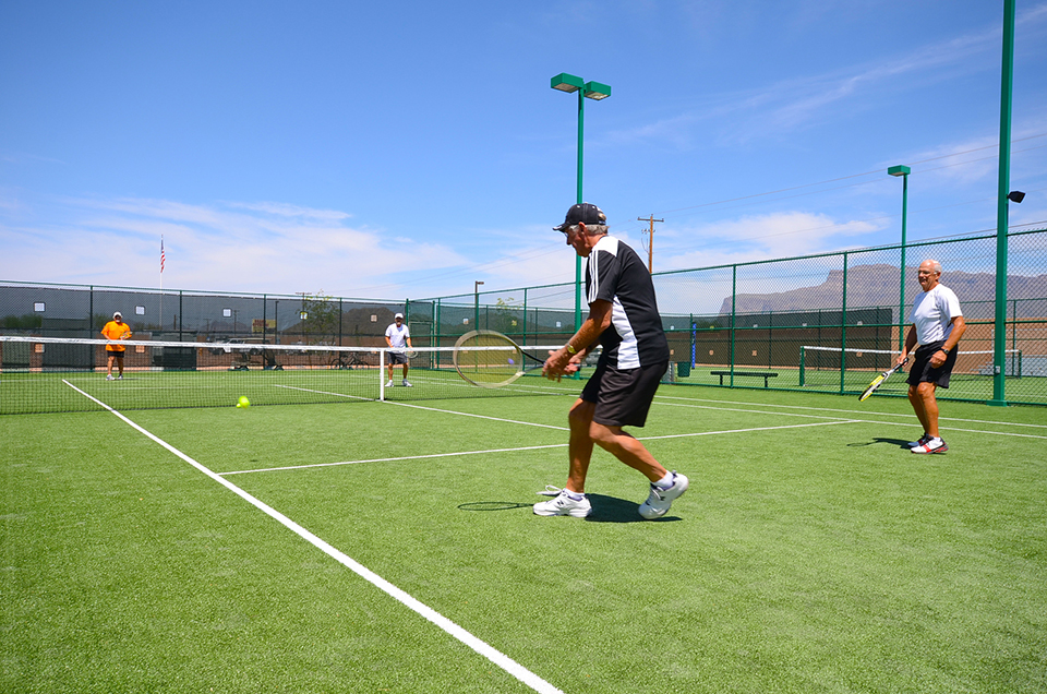 Older male residents playing a game of tennis on one of the four tennis courts on the property.