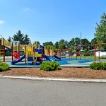 Large open playground area for both older and younger children with slides, swings, and jungle gym.