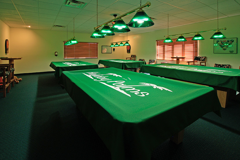 Billiards room offering 4 pool tables, chairs, tables, 2 dart boards, and lighting above each table