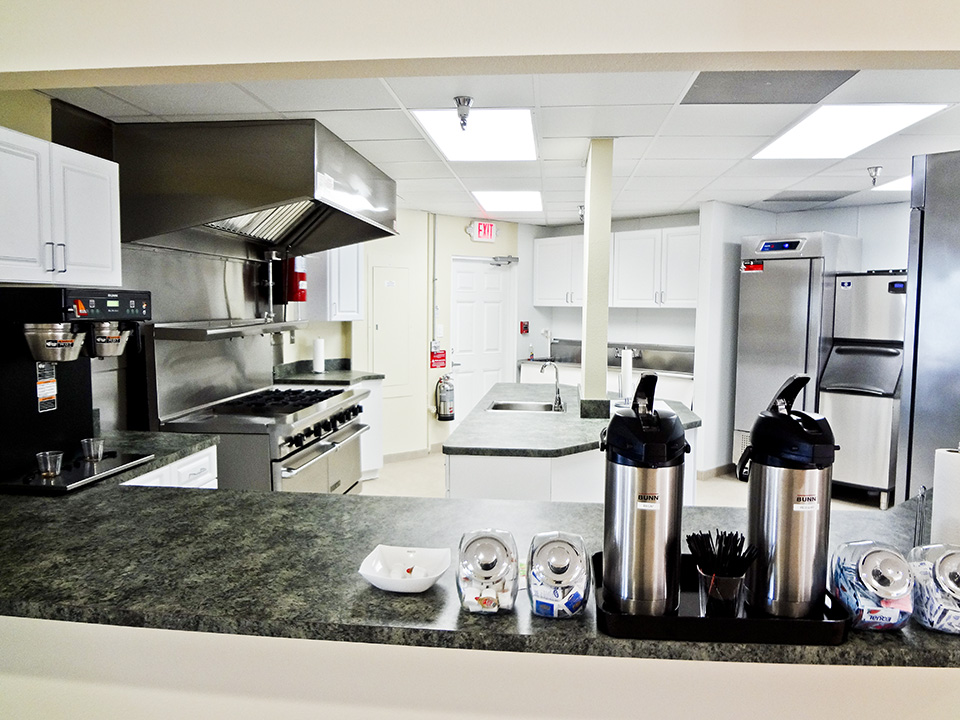 Very modern commercial kitchen is located in the clubhouse. Stainless steel oven, fridge, and ice chest. Large island with sink. White cabinets with dark granitetops for counters.
