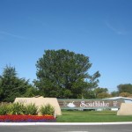 Large front entrance sign into Southlake Mobile. Surrounded by beautiful red, purple, and yellow flowers and well maintained grass.
