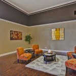 Modern and open concept clubhouse. The warm tones of orange, brown, and yellow create a welcoming home feel. Circular seat arrangement allow residents to lounge and relax.
