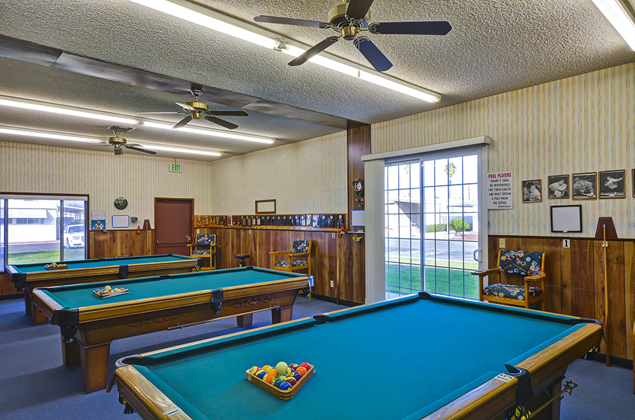 Billiards room equipped with three pool tables for residents to freely use. Old wood panels line the lower half of the walls to give an old saloon feel.