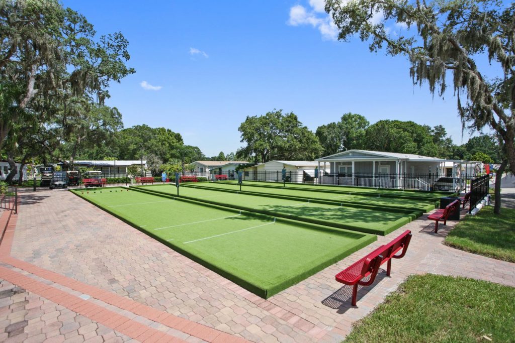 Clean bocce ball fields with red benches for seating are an amenity at Island in the Sun.