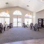 Clubhouse with mini library. Comfy chairs with tables and lamps for reading. Lots of natural light with tall windows with arches.