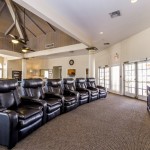 Clubhouse with tall vaulted ceilings. Comfy recliner chairs in lounge area with TV mounted on wall for viewing.
