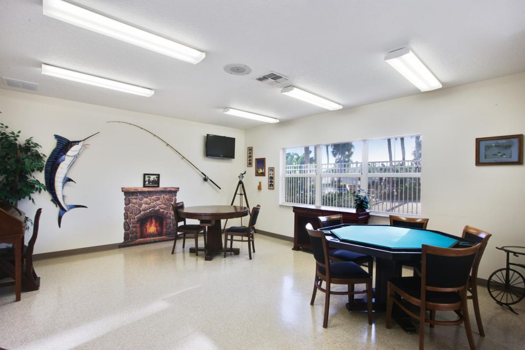 Bright game room with card tables. Giant fish and fishing rod on wall for decor.