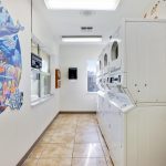 Laundry room at Fountainview Estates, a 55+ manufactured home community. Stacked washers and dryers run along the wall. A mural of ocean life painted onto one wall inside laundry room.