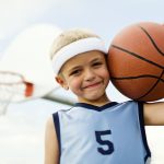 A young boy plays holds the basketball smiling.