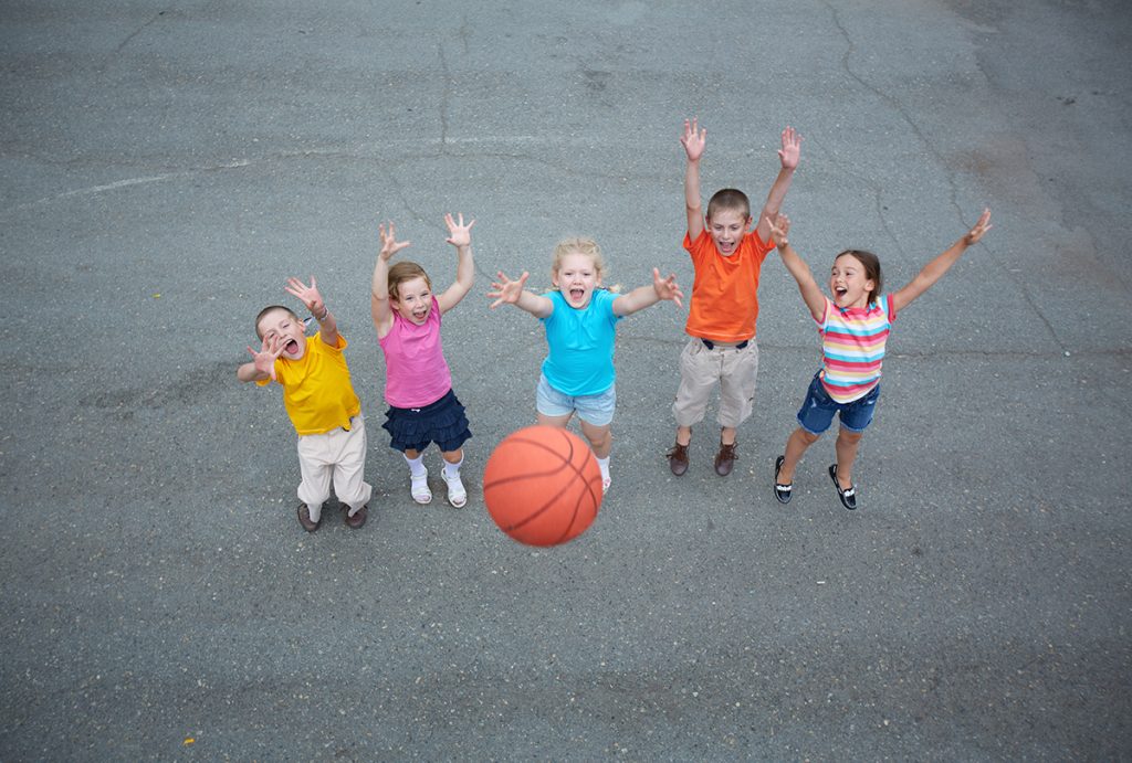 Five children playing basketball on the basketball court.