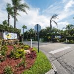 Palm Breezes Club has a well marked entrance with two signs on either side and flowing palm trees. Nicely landscaped with green grass and shrubbery.