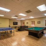 Palm Beach Plantation, an all age manufactured home community, offers a large game room with a pool table and ping pong. A loveseat and a flat screen tv are set up for movie time.