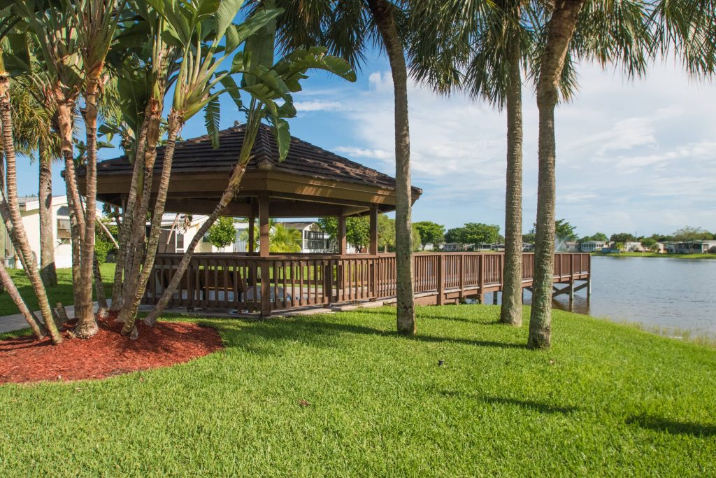 Large gazebo with covered seating at one end of dock. Lush landscape all around.