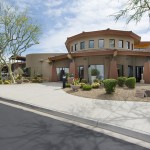 Montesa at Gold Canyon has a dome shaped community center with trees, cactus, and shrubbery landscaped around it outside