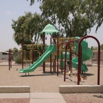 Playground for children with swings, two slides and monkey bars.