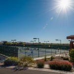 A sunny, cloudless day. People play pickleball at the pickleball courts.