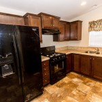 Open kitchen space within a home on the property. Cream tile flooring throughout, wood cabinets, cream granite counter tops, and cream tile backs-plash
