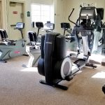 Fitness center with treadmill, stationary bikes, elliptical machine and weight machine.