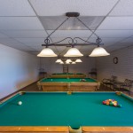 A billiards room with 3 pool tables and seating.