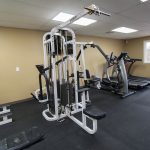 A fitness room with 2 treadmills, elliptical and a weight machine