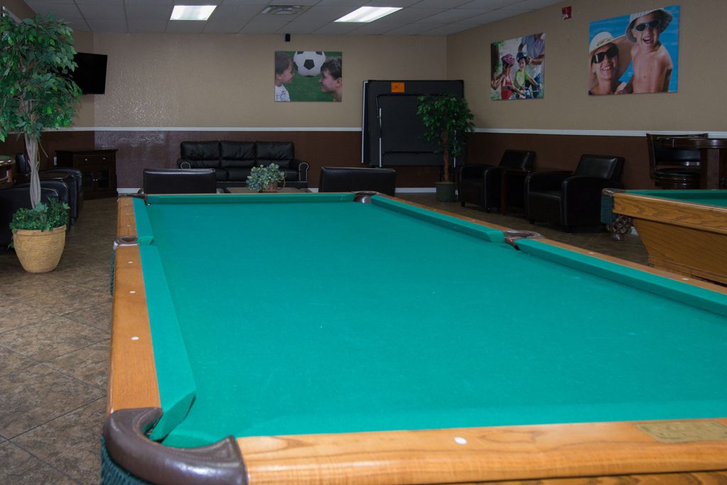 A billiards room with two pool tables. Pictures of families on the wall