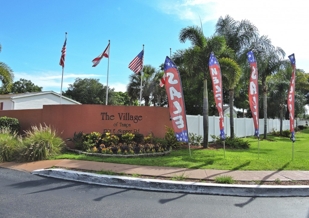 Village of Tampa, an all age manufactured home community's entrance is marked clearly with Flags that hover over the sign.