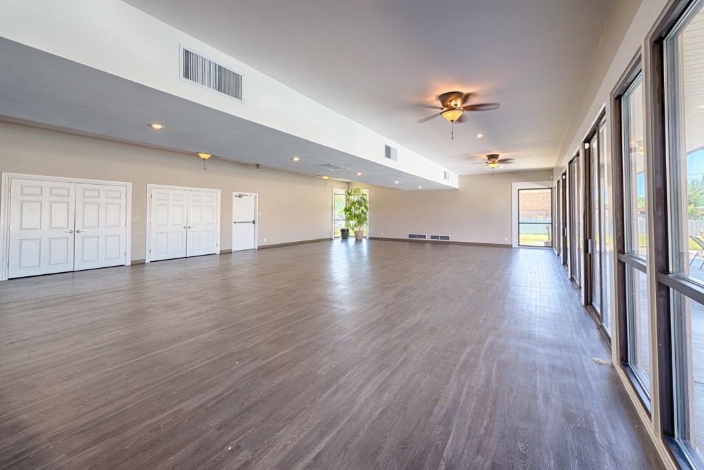 Beautiful hardwood floors and open space in the clubhouse with lots of natural light coming in due to a wall of windows.