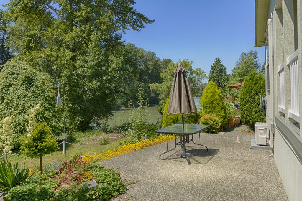 Outdoor area with a picnic table overlooking the Puyallup River. Beautiful view of river and luscious greenery.