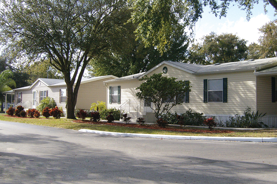 Wide clean paved streets and tall lush trees through out the community and with manufactured homes.