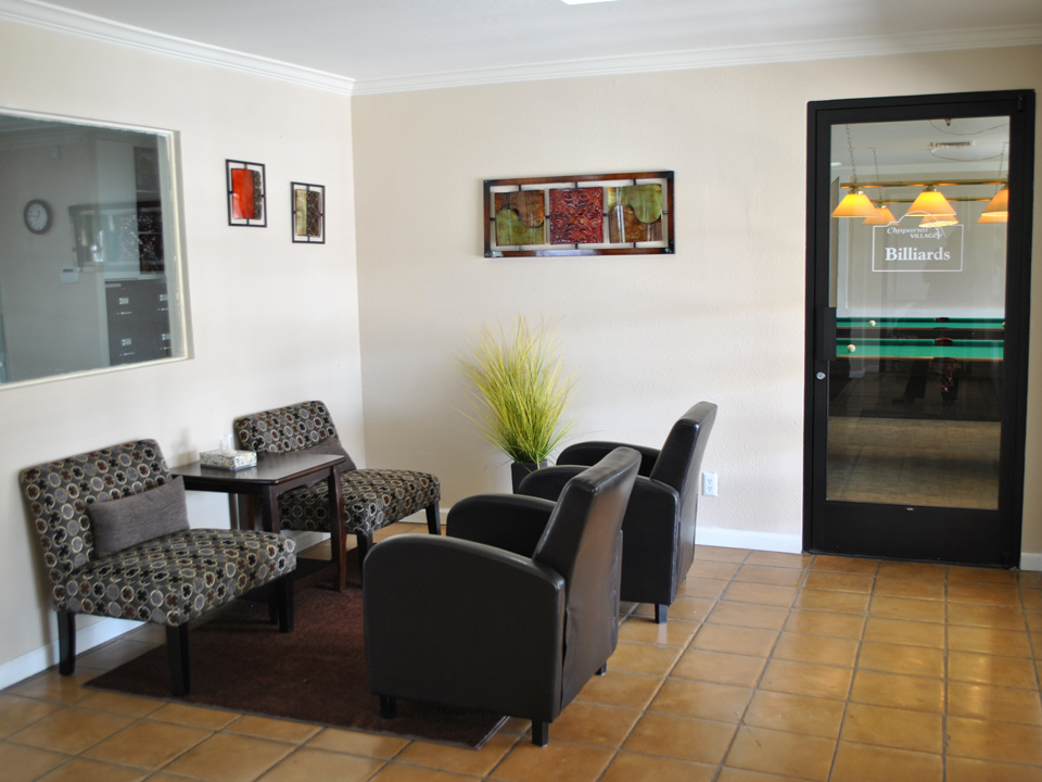 The lobby of the welcome center has cushioned chairs and has an entrance door to the billiards room.