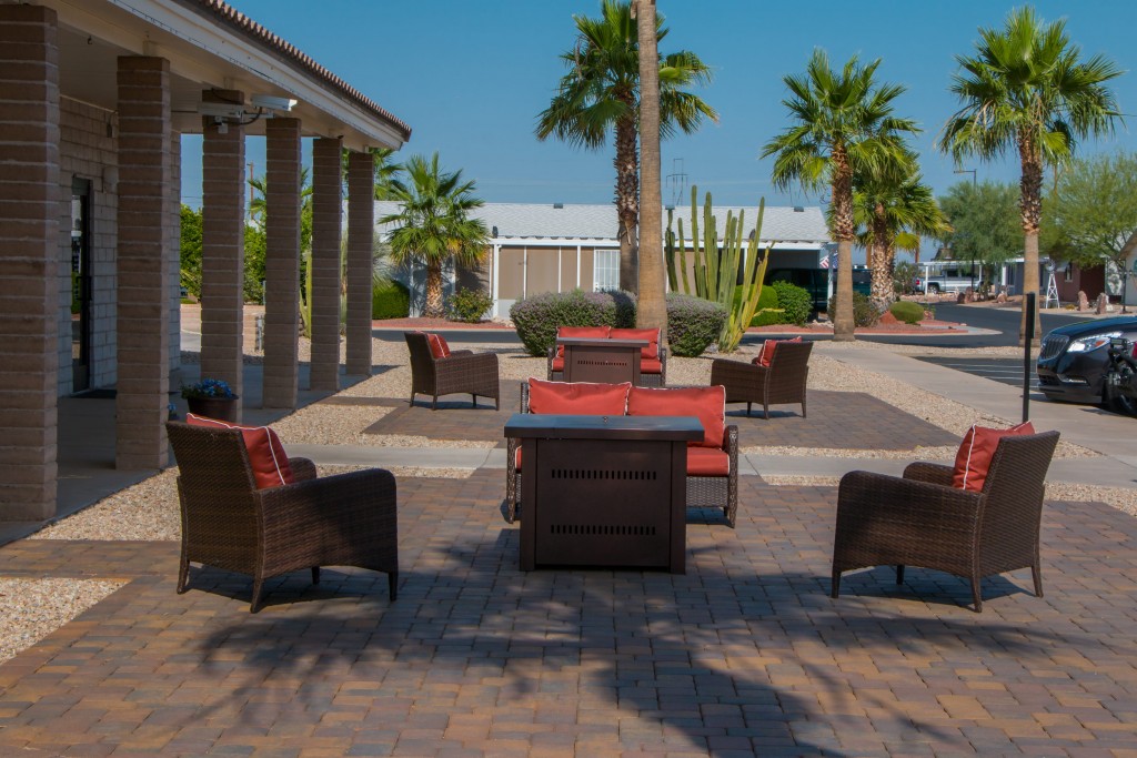 Cushioned seating sits outside the office surrounded by Palm trees.
