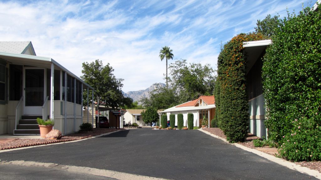 A quiet, peaceful, clean neighborhood with shade trees and mountains as the background.