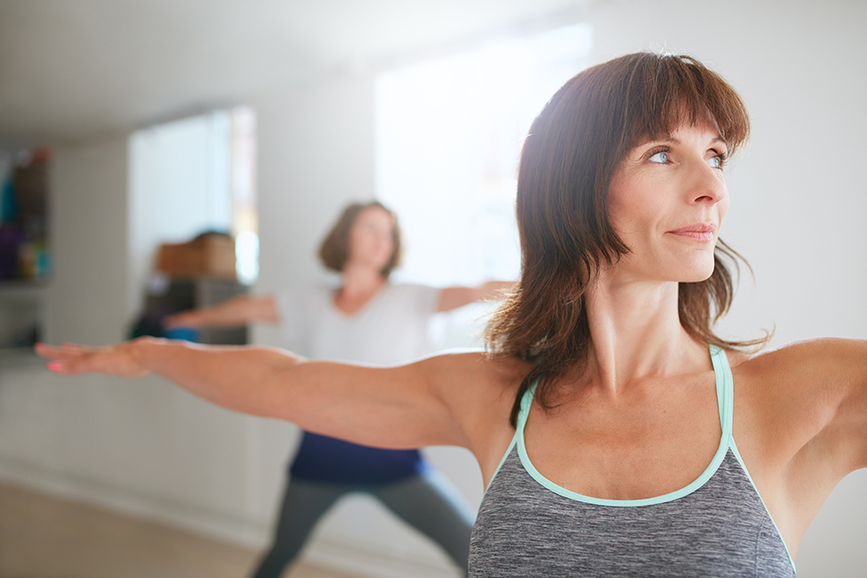 Portrait of beautiful older woman doing the warrior pose during yoga class.