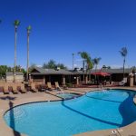 Beautiful poolside view with multiple chairs situated around for relaxation. Access to the community club house and outdoor dining area.